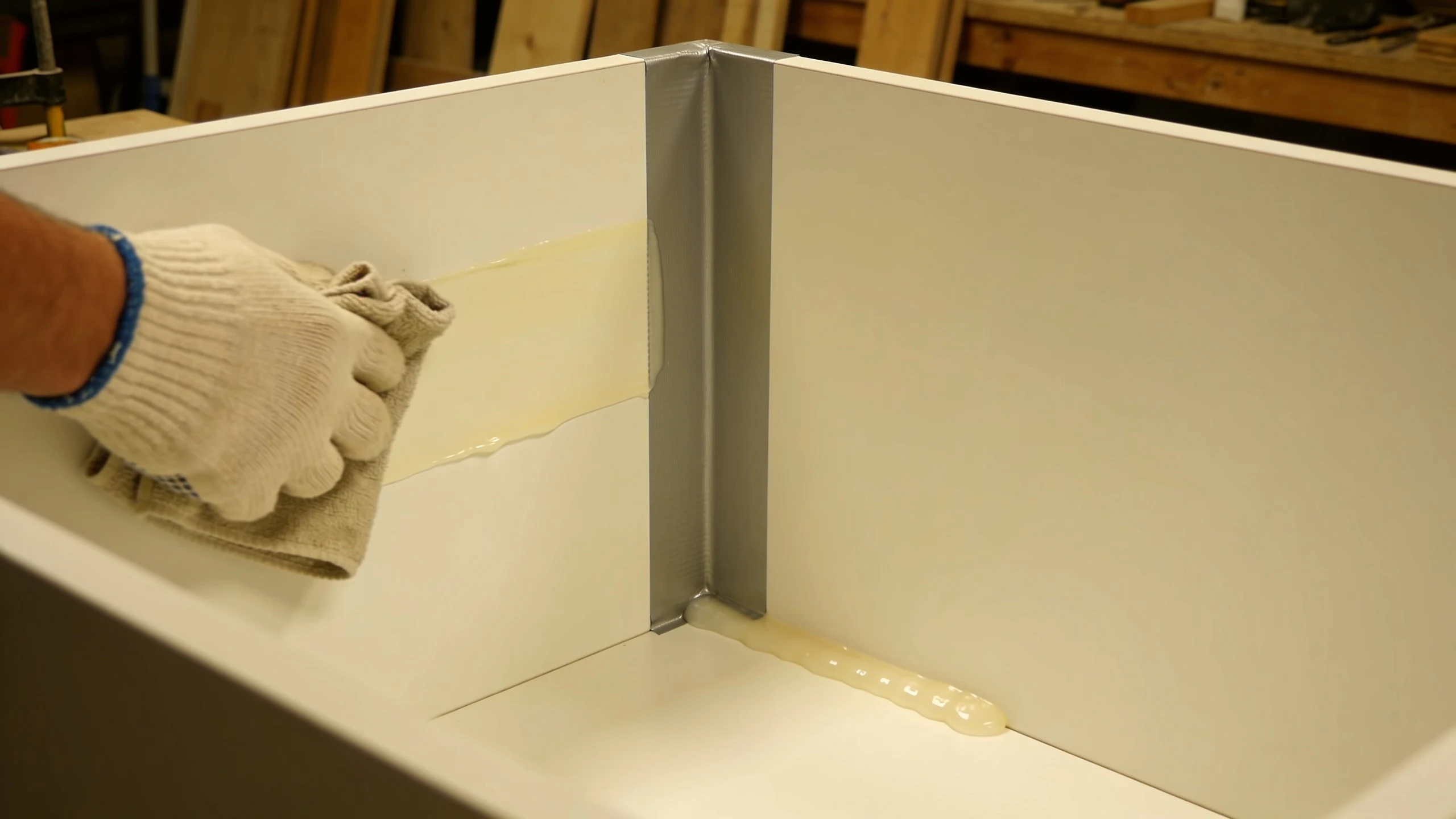 Applying paste wax and caulk inside the corner of an epoxy table mold